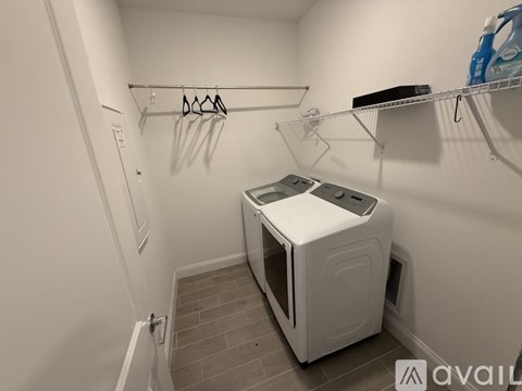 A white dryer is sitting in a small, white-walled laundry room.