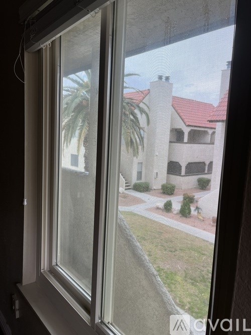A window with a view of a building and a palm tree.