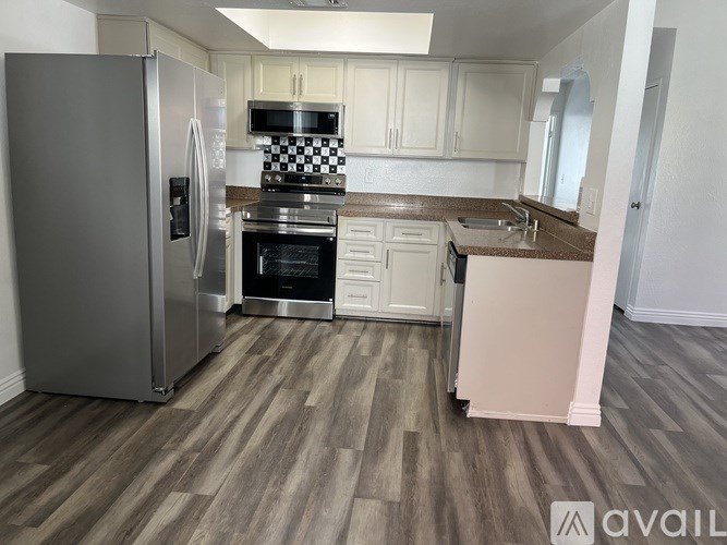 A kitchen with a refrigerator, oven, and sink.