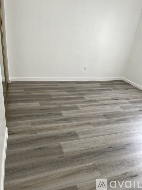 A room with wooden flooring and white walls.