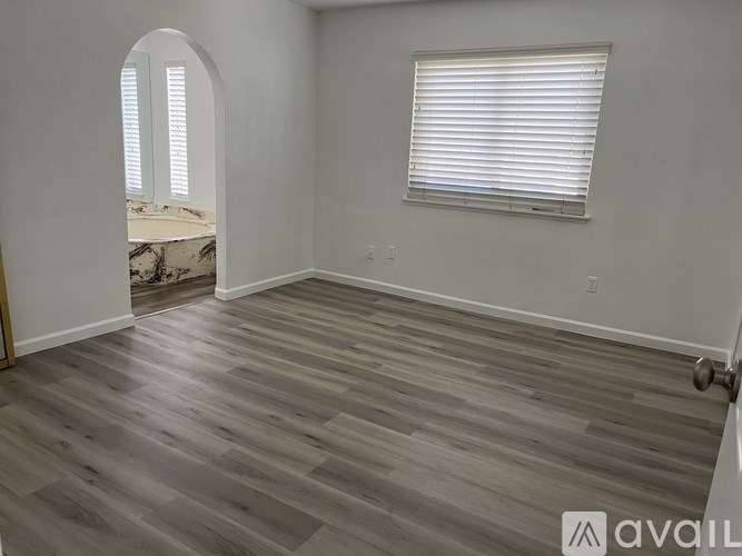 A room with a wooden floor and a window with blinds.
