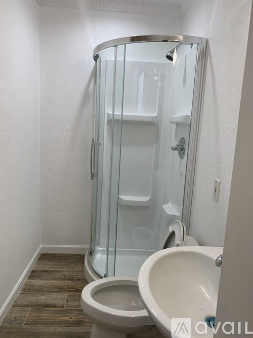 A white toilet with a glass shower stall in the background.