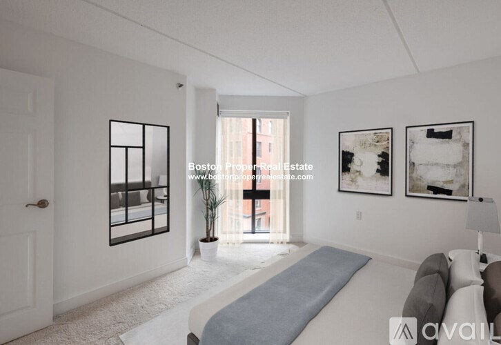 A living room with a couch, a window, and two pictures on the wall.