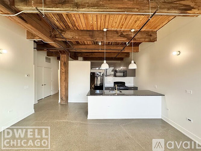 A large open space with a kitchen island and pendant lights.