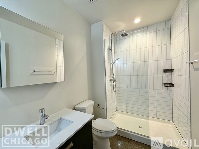 A white tiled bathroom with a toilet, sink, and shower.
