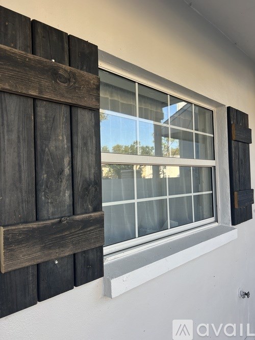 A window with wooden shutters on a white wall.