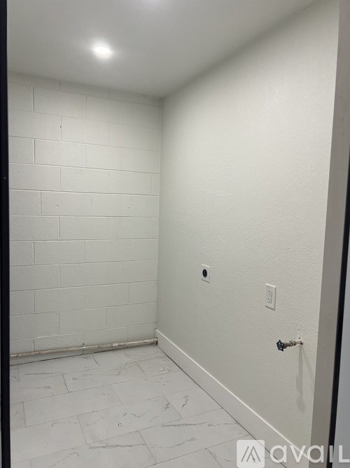 A white tiled bathroom with a door and a light switch.