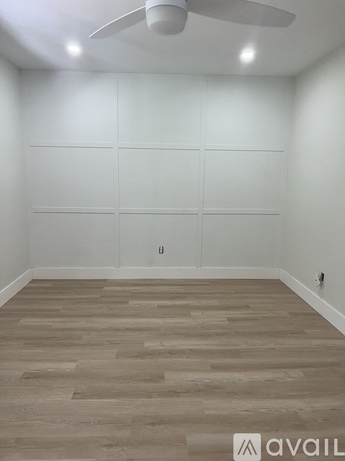 A room with wooden flooring and white walls.
