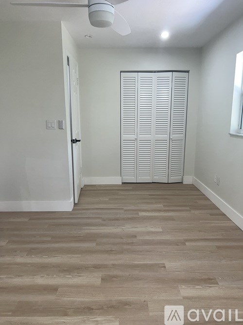 A room with a white door and a white ceiling fan.