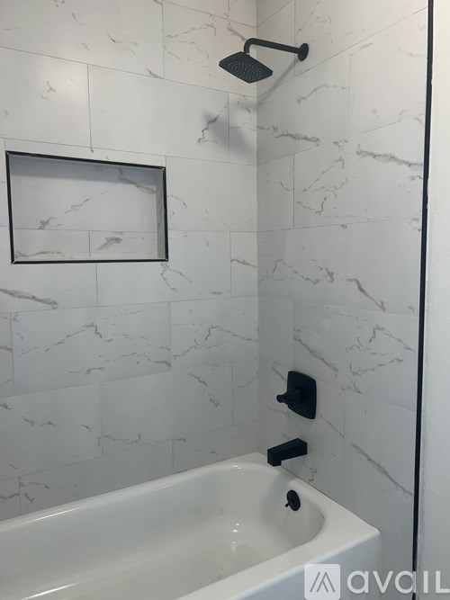 A white bathroom with a marble tile wall and a white tub.