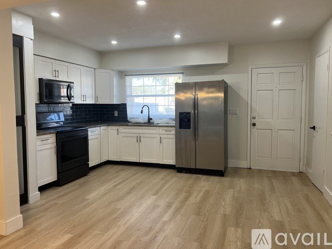 A kitchen with a refrigerator, sink, and cabinets.