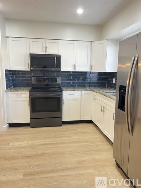 A kitchen with white cabinets and a black stove top oven.