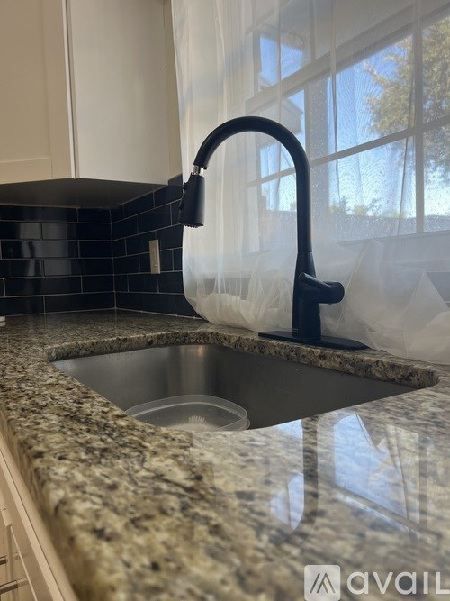A kitchen sink with granite countertop and black faucet.