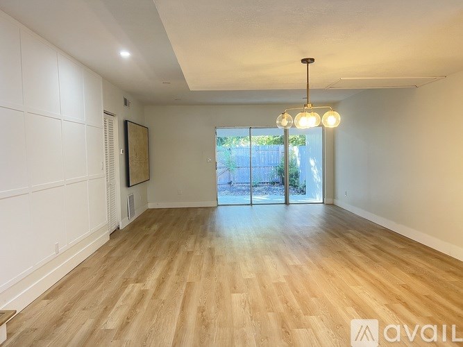 A spacious room with wooden flooring and a chandelier hanging from the ceiling.