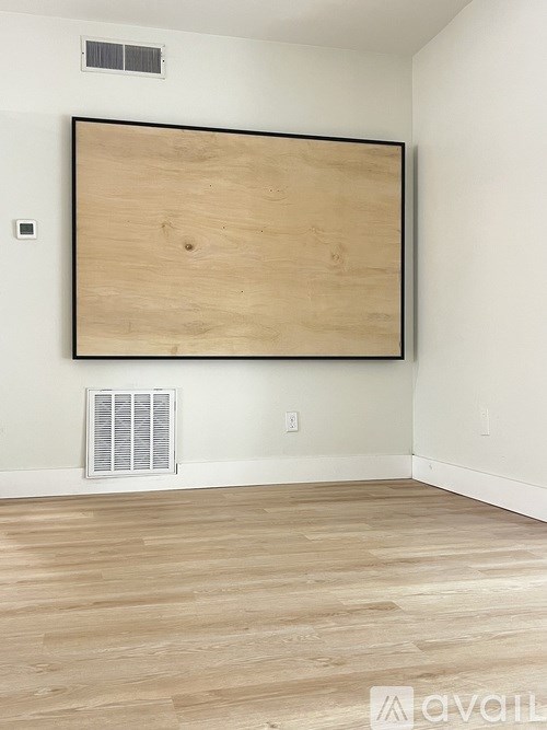 A room with a wooden board on the wall and a window with blinds.