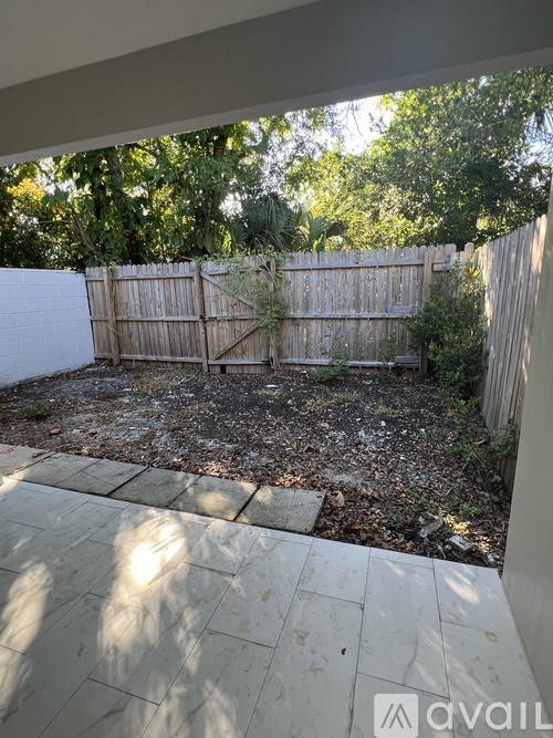 A backyard with a wooden fence and a concrete patio.