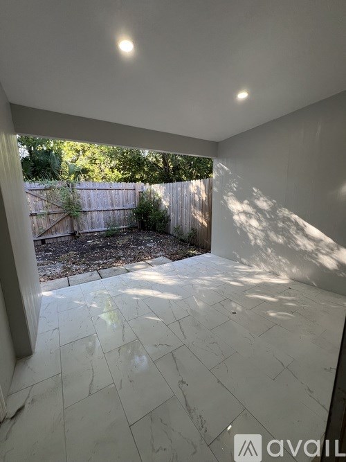 A sunlit room with a tiled floor and a view of a backyard.