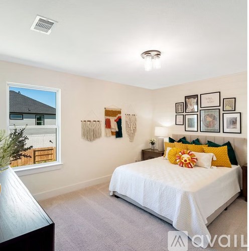 A bedroom with a bed, a window, and pictures on the wall.