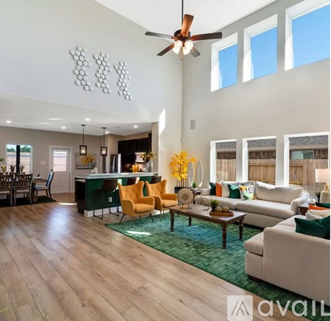 A living room with a green rug and a wooden floor.