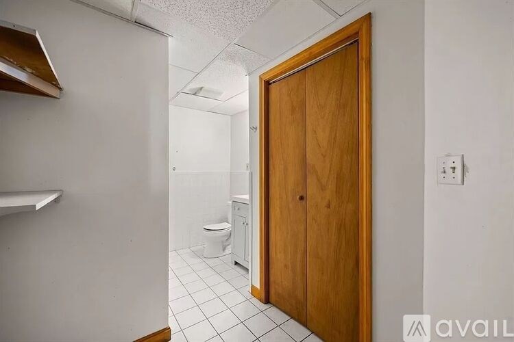 A bathroom with a toilet, sink, and wooden door.