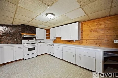 A kitchen with white cabinets and a brick wall.