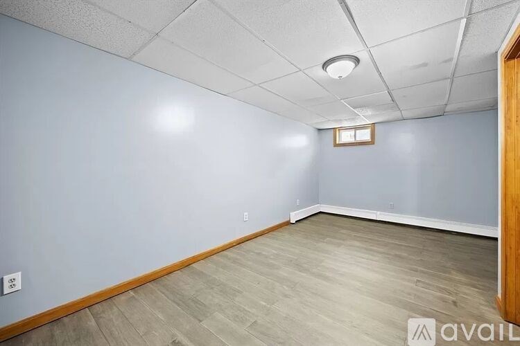 A room with light blue walls and wooden flooring is available for rent.