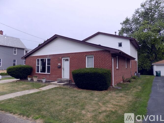 A house with a red brick exterior and a white door is for sale.