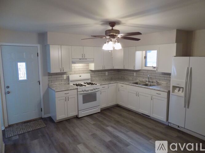A kitchen with white cabinets and a wooden floor.