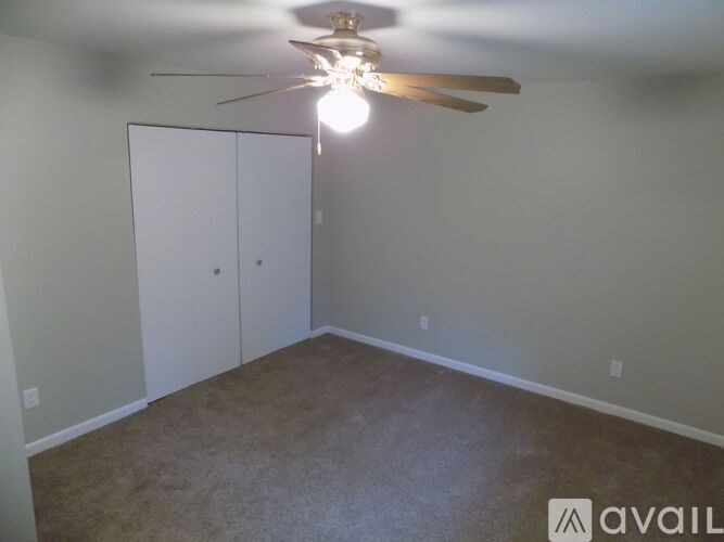 A room with a ceiling fan and a white closet door.