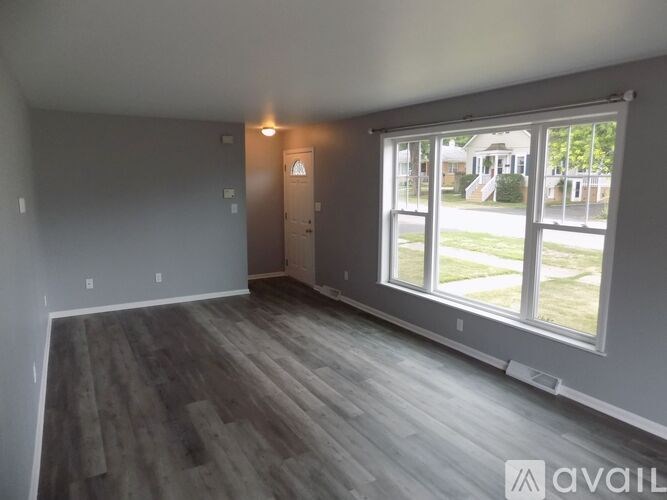 A room with grey walls and wooden flooring is available for rent.