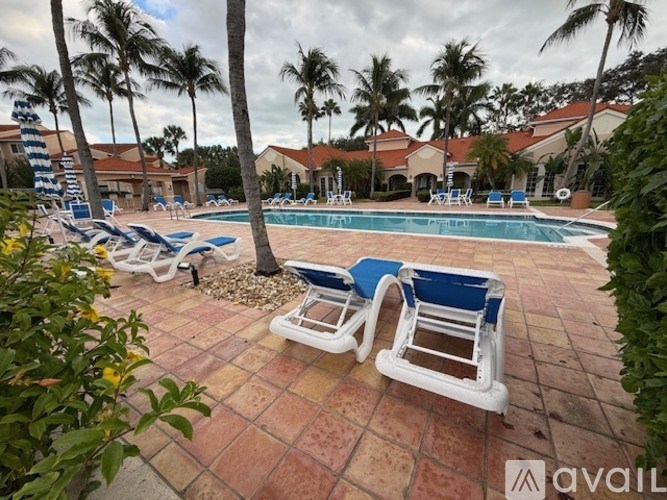 A pool surrounded by palm trees and blue and white chairs.