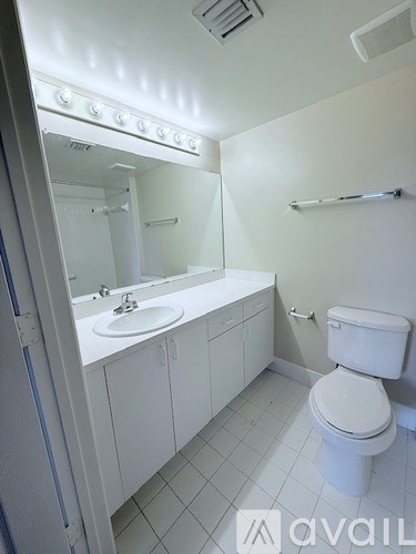 A white bathroom with a toilet, sink, and mirror.