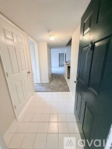 A hallway with white tiled floors and white doors.