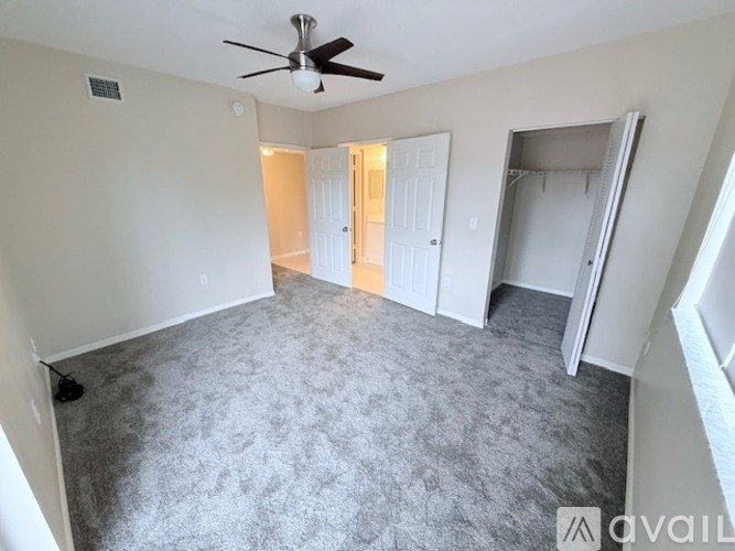 A room with a ceiling fan and carpeted floor.