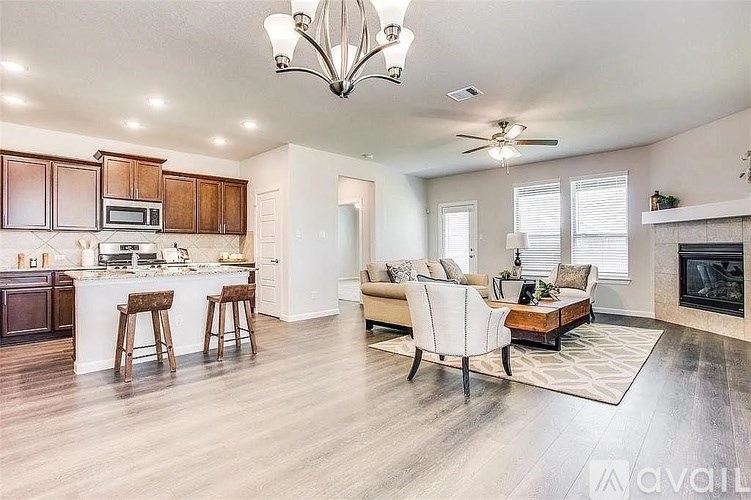 A well-lit, spacious living room with a kitchen area in the background.