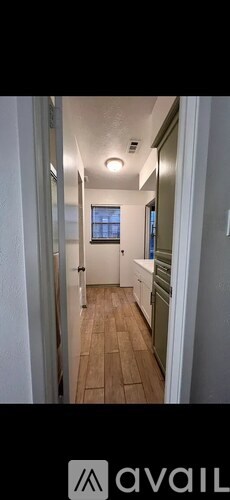 A hallway with wooden floors and white walls.