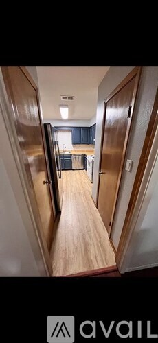 A hallway with wooden floors and doors on either side.