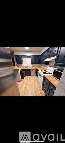 A kitchen with dark cabinets and a wooden floor.