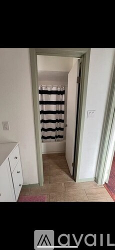 A hallway with a striped curtain and a white cabinet.