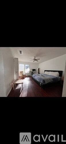 A bedroom with a bed, a chair, and a ceiling fan.