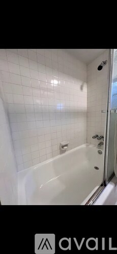 A white tiled bathroom with a bathtub and shower.