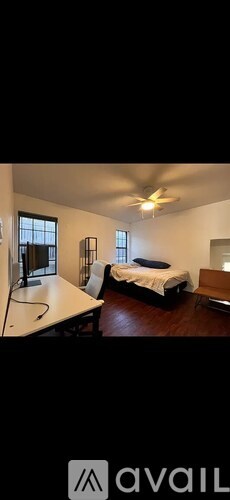 A bedroom with a bed, a desk, and a chair.