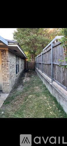A narrow alley with a wooden fence on one side and a brick building on the other.