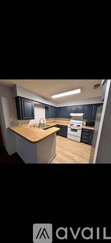 A modern kitchen with dark cabinets and a wooden island.