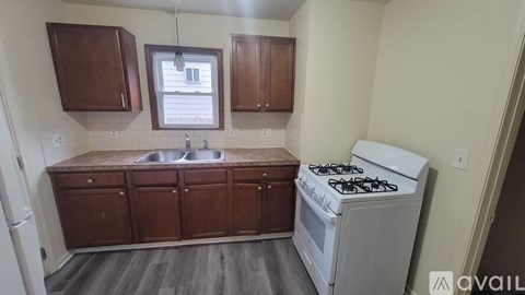A kitchen with a white stove and wooden cabinets.