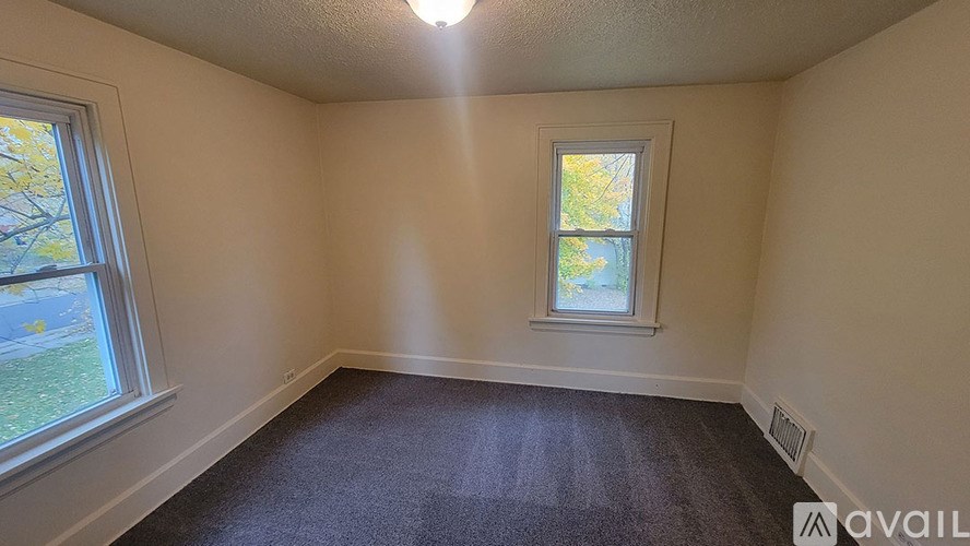 A room with a carpeted floor, a window, and a ceiling light.