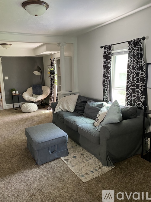 A living room with a grey couch and a round white chair.