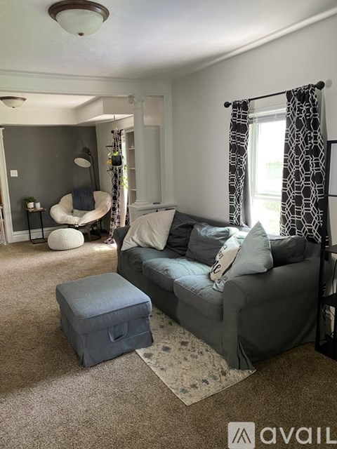 A living room with a grey couch and a round white chair.