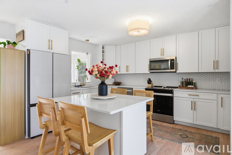 A kitchen with a white island and wooden chairs.