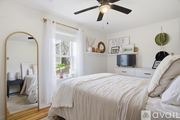 A bedroom with a large bed, a ceiling fan, and a mirror.